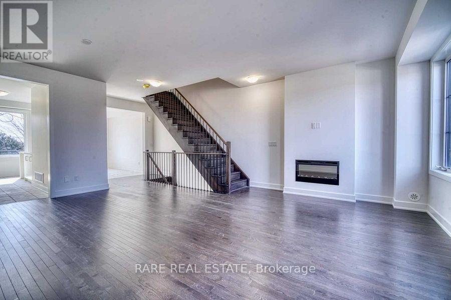 A spacious room with a staircase and a fireplace.