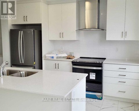 A kitchen with white cabinets and a stainless steel refrigerator.