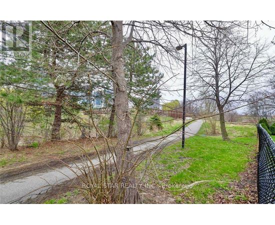 A road with a fence on the right side and trees on the left.