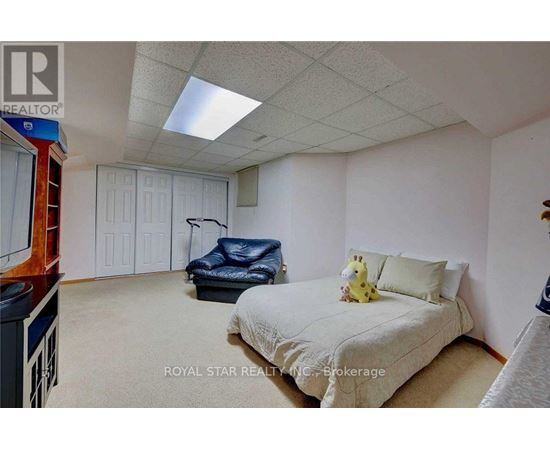 A bedroom with a bed, a chair, and a teddy bear on the bed.