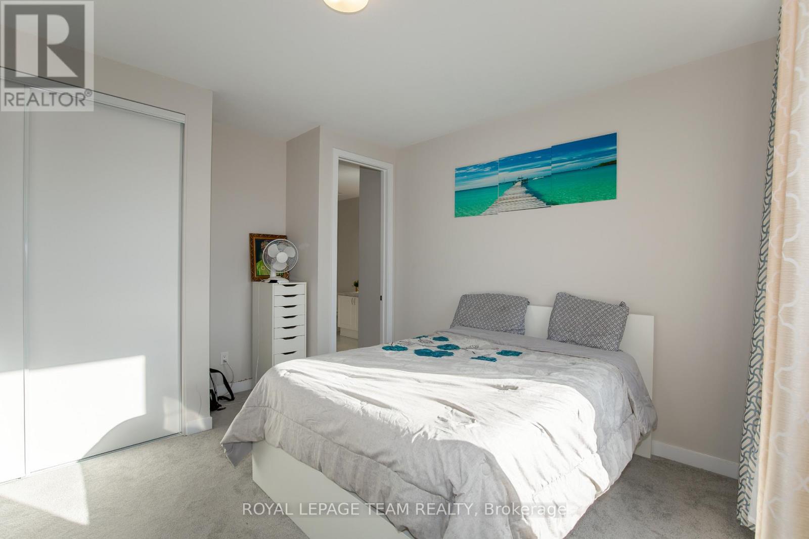 A bedroom with a large bed and a painting on the wall.