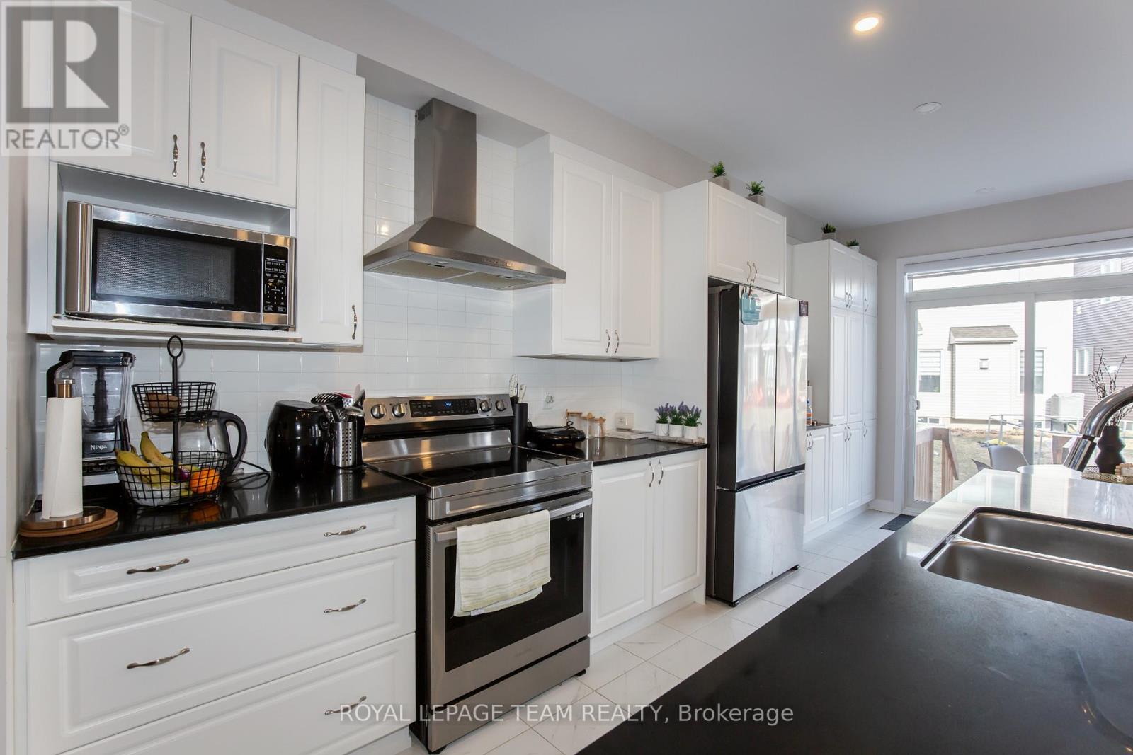 A modern kitchen with white cabinets and black countertops.