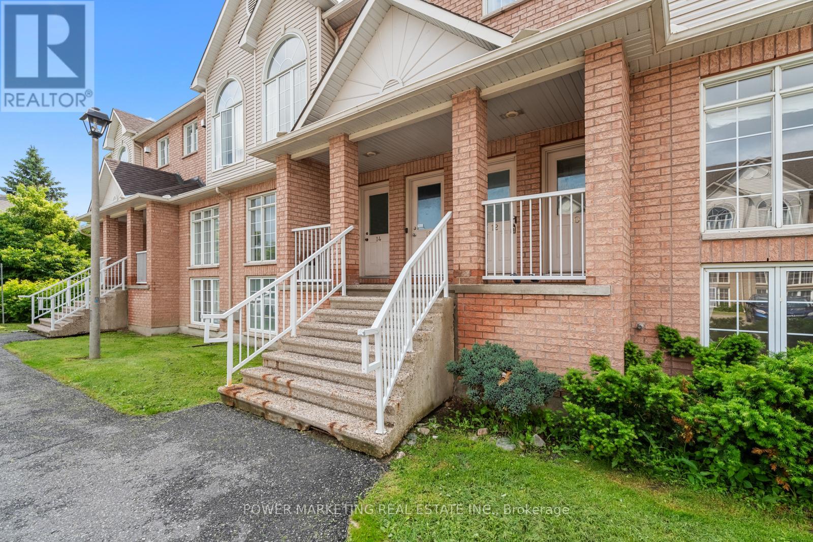 A red brick house with a white porch and stairs leading to the front door.