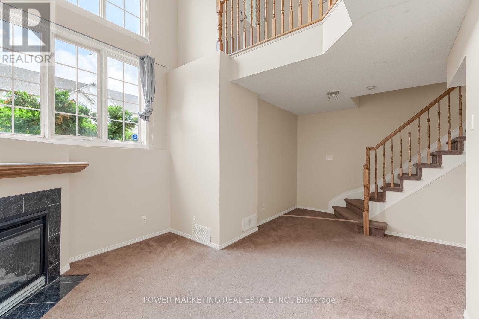 A spacious living room with a fireplace and a staircase.