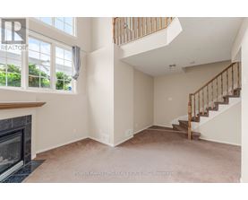 A spacious living room with a fireplace and a staircase.