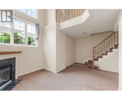 A spacious living room with a fireplace and a staircase.
