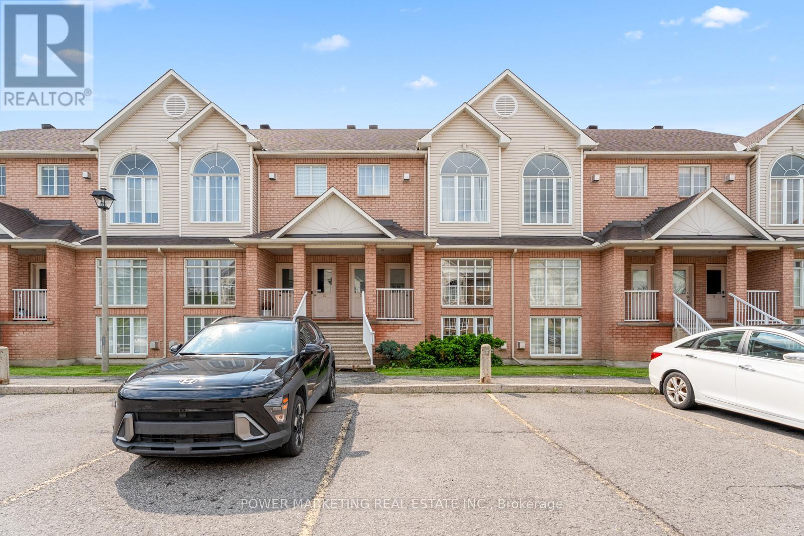 A black car is parked in front of a building with a sign that reads "REALTOR".