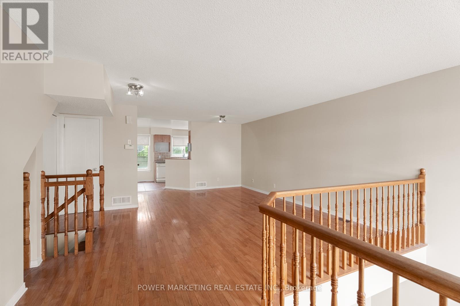 A spacious room with wooden floors and a staircase.