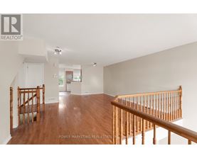 A spacious room with wooden floors and a staircase.