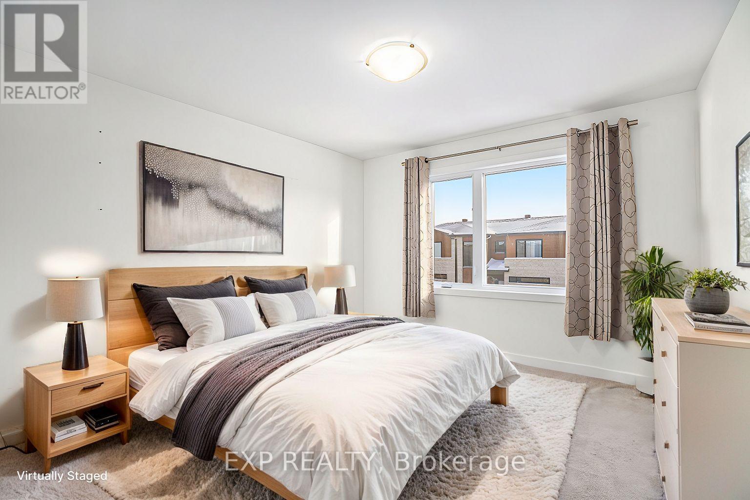 A bedroom with a large bed, a nightstand with a lamp, a window with curtains, and a painting on the wall.