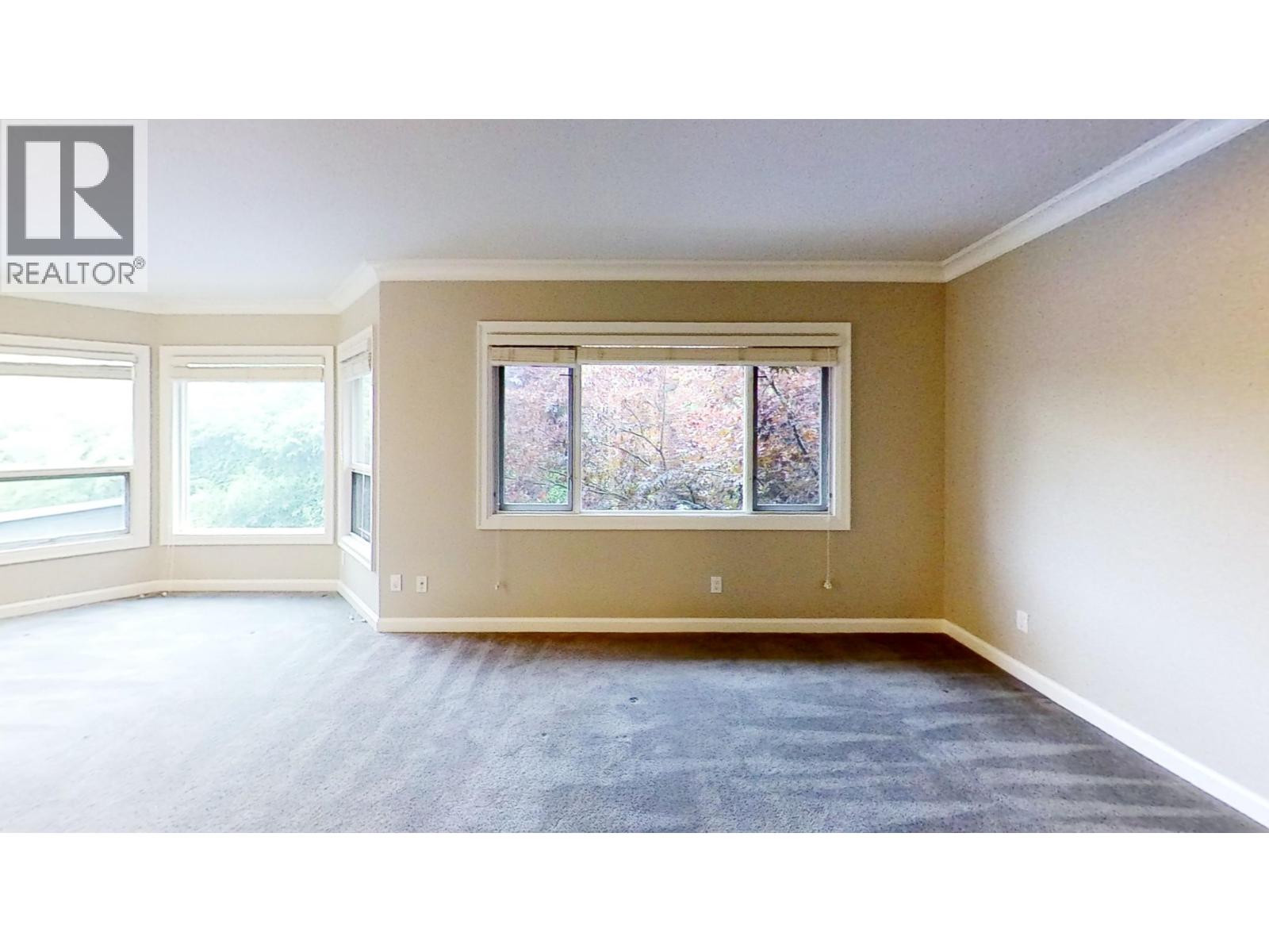 A large empty room with a window overlooking trees.