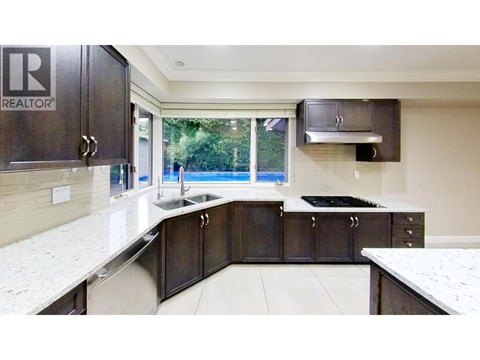 A kitchen with dark brown cabinets and white countertops.