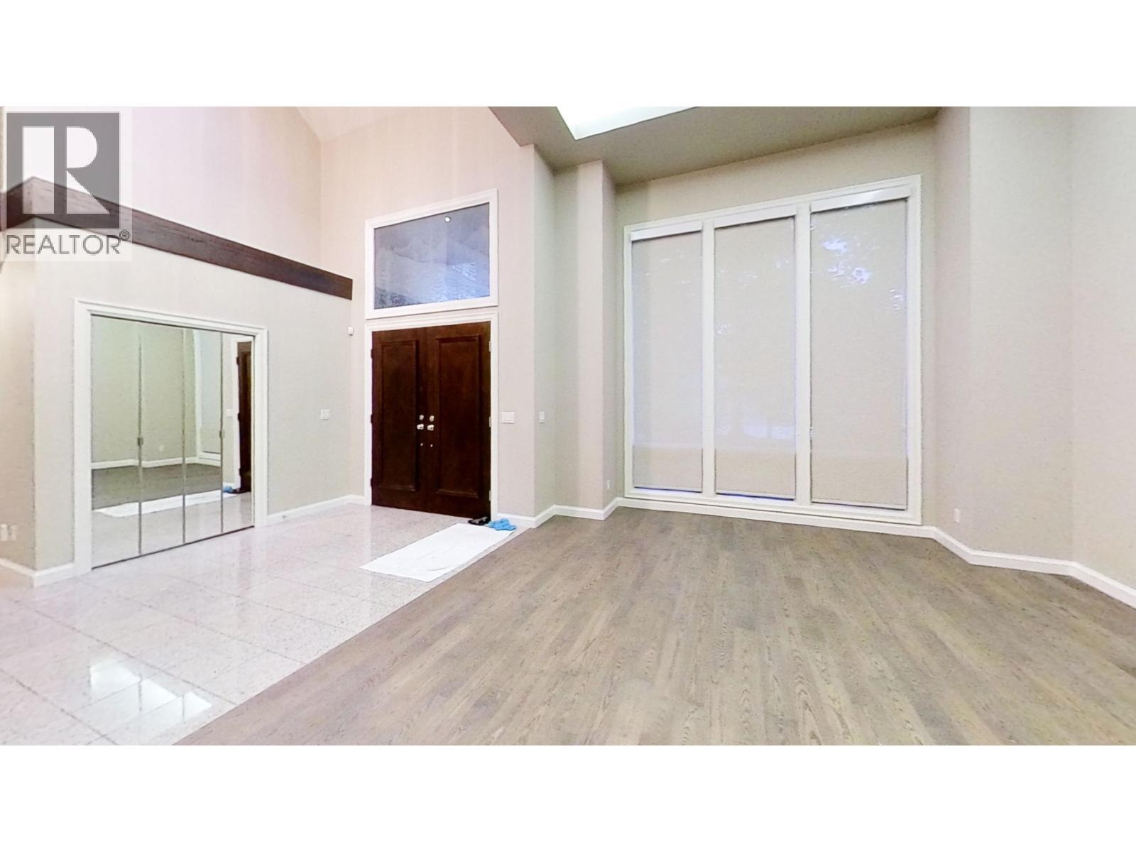 A spacious room with a wooden floor and a large window.