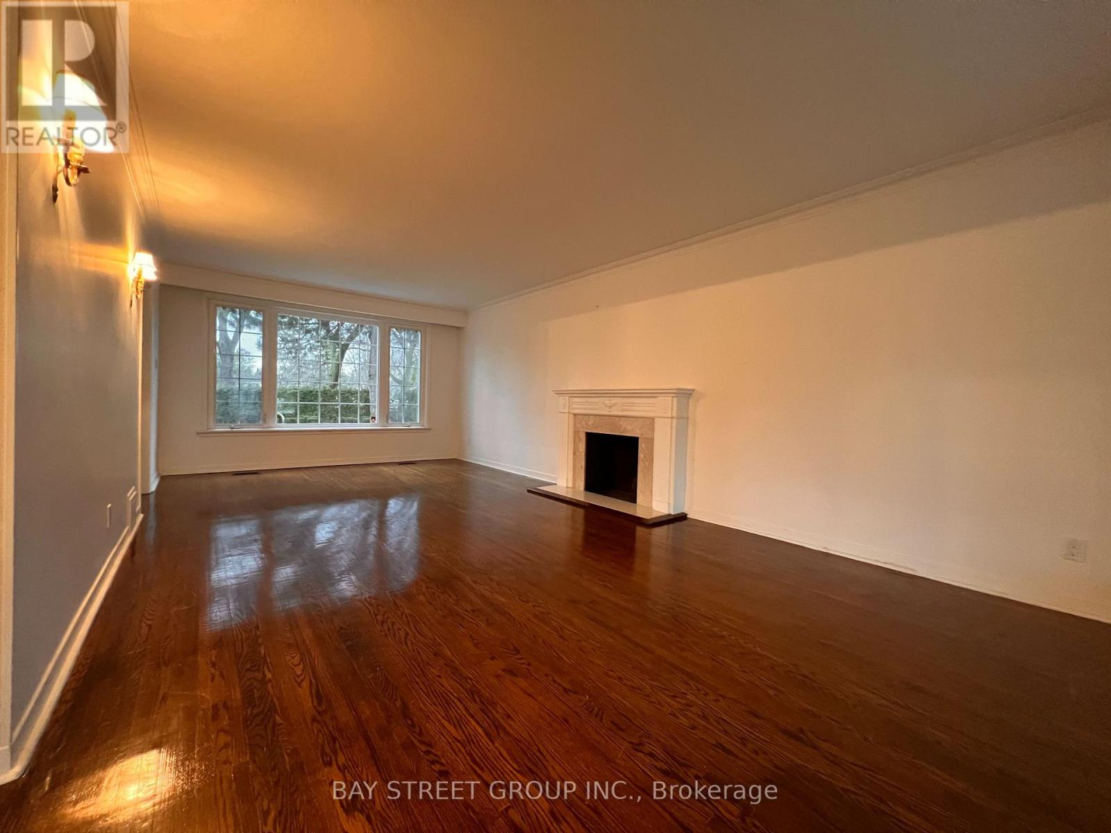 A spacious room with a fireplace and wooden floors.