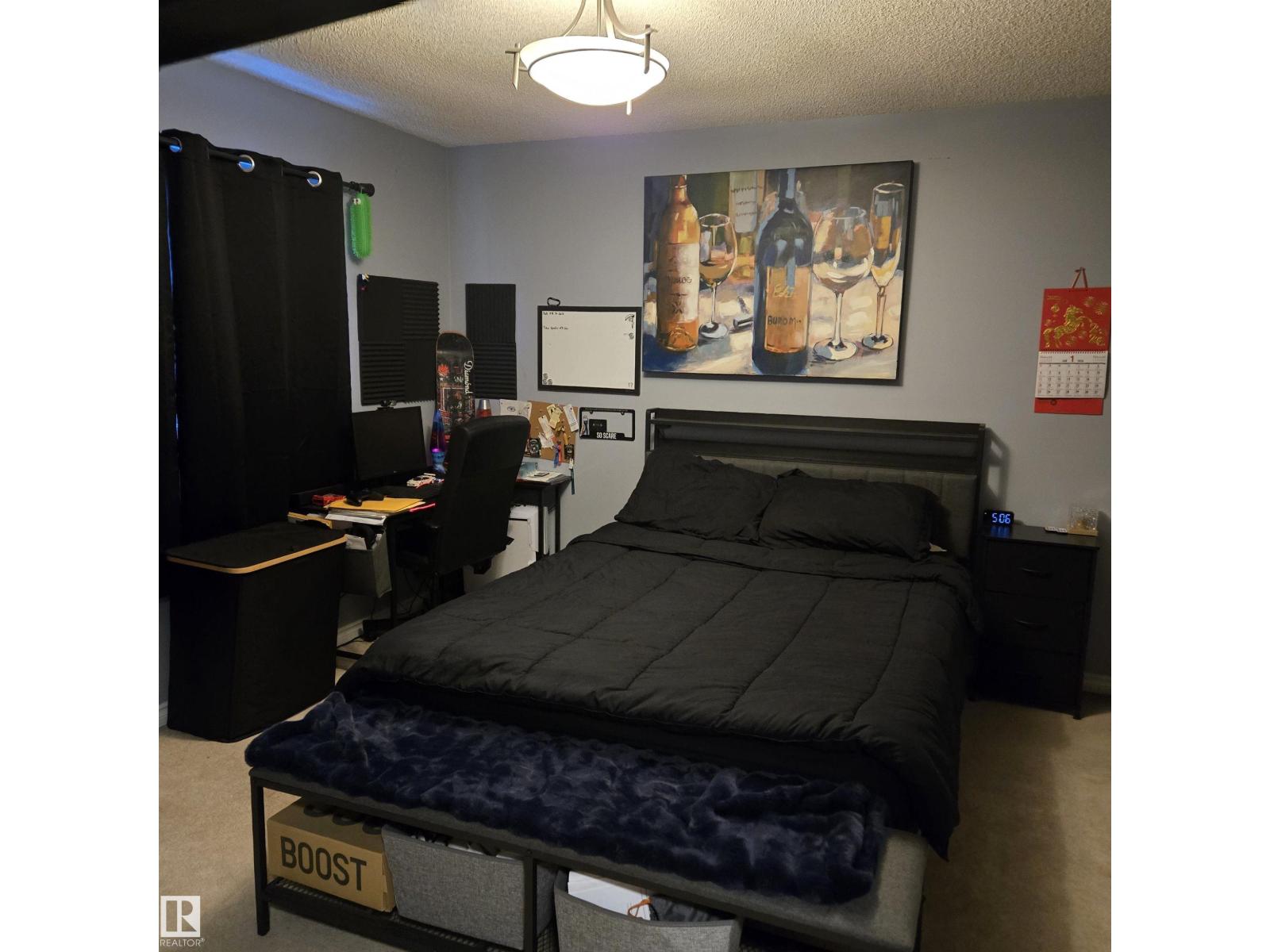 A bedroom with a bed labeled "BOOST" and a painting of wine glasses on the wall.