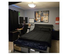 A bedroom with a bed labeled "BOOST" and a painting of wine glasses on the wall.