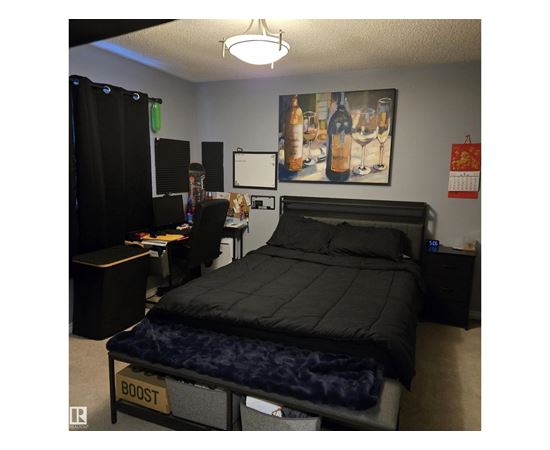 A bedroom with a bed labeled "BOOST" and a painting of wine glasses on the wall.