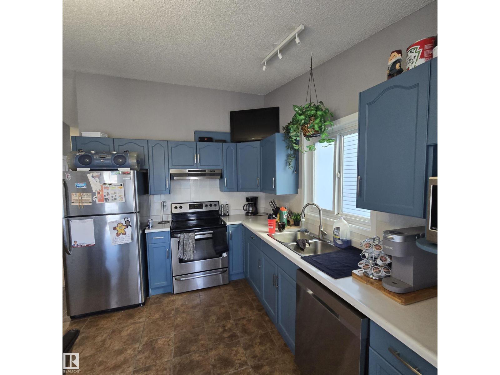 A kitchen with blue cabinets and a stainless steel refrigerator.