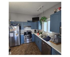 A kitchen with blue cabinets and a stainless steel refrigerator.