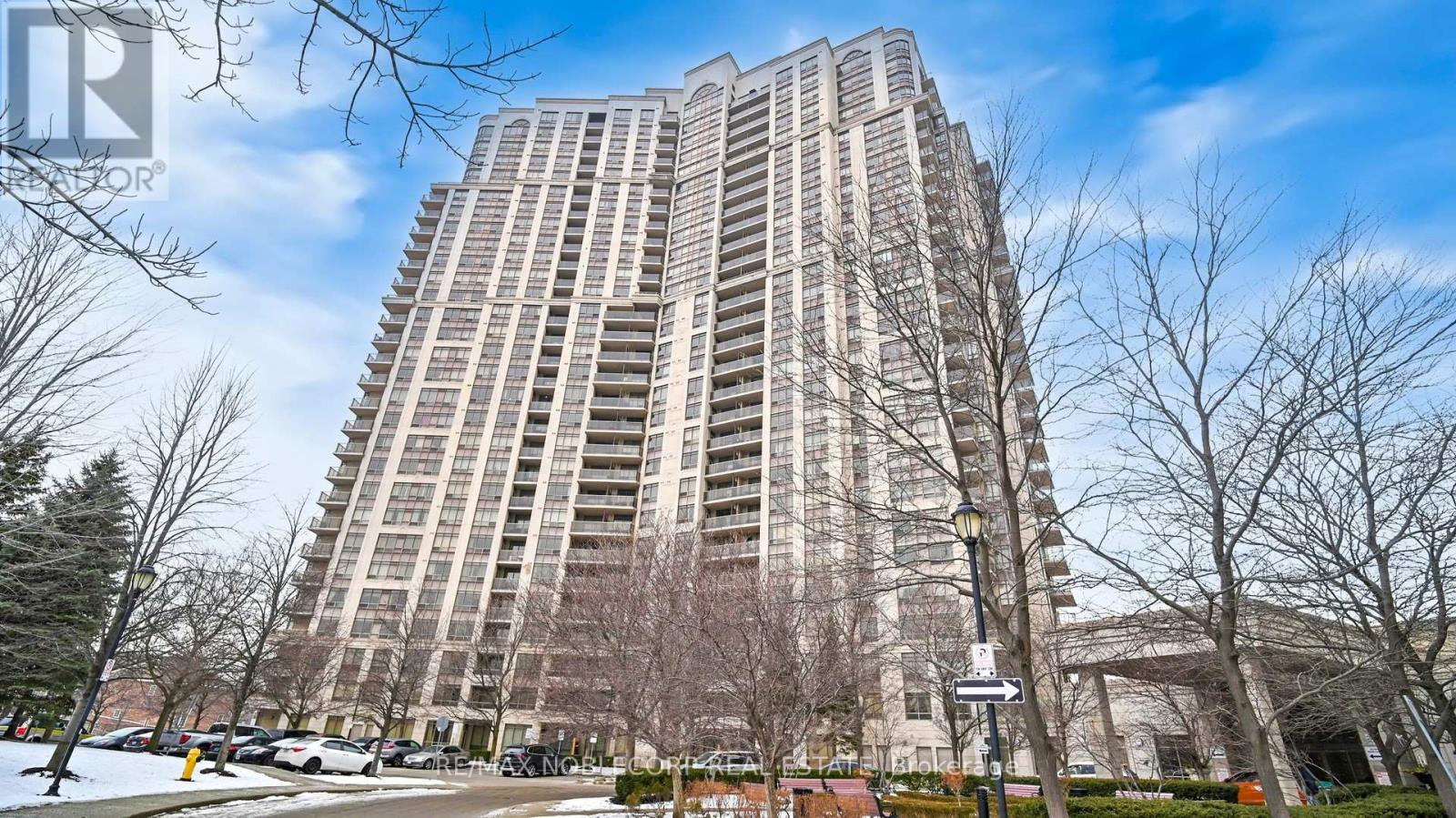 A tall residential building with a parking lot in front.