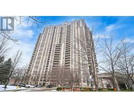 A tall residential building with a parking lot in front.