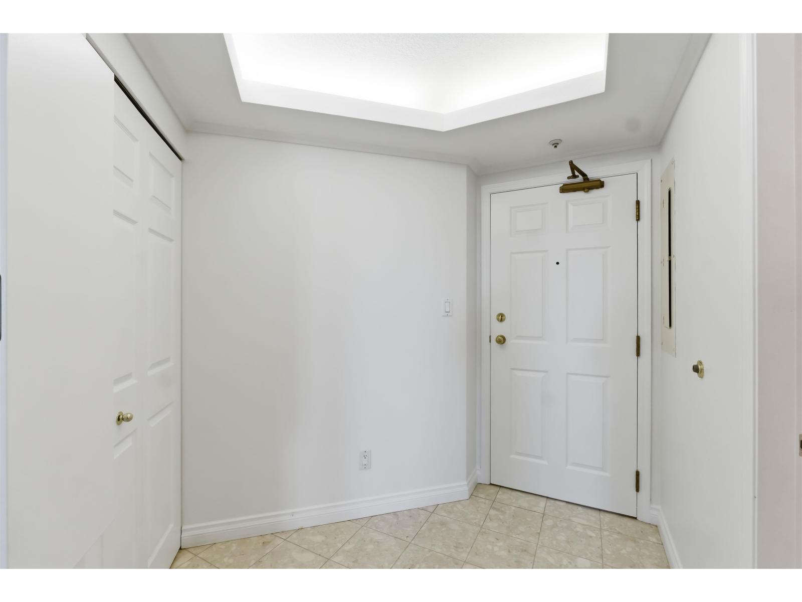 A white door with a gold handle is in a room with white walls.