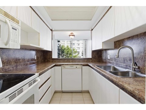 A kitchen with white cabinets and a black countertop.