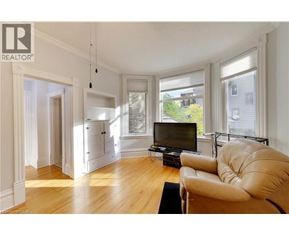 A living room with a tan leather couch and a television.