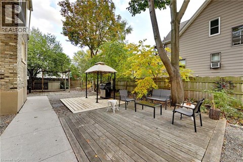 A gazebo sits on a wooden deck in a backyard.