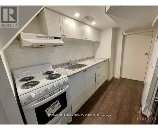 A kitchen with a stove top oven and white cabinets.