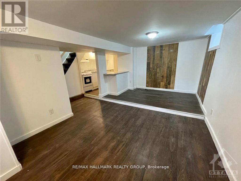 A spacious room with wood flooring and a staircase leading to the upper level.