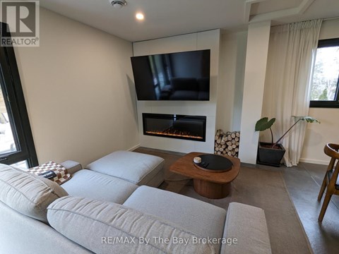 A modern living room with a grey sofa and a flat screen TV mounted above a fireplace.