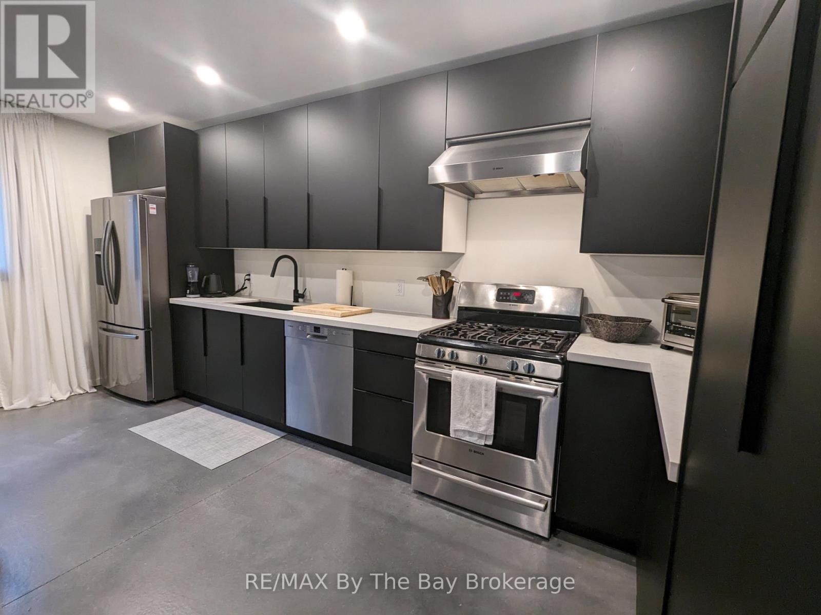 A modern kitchen with a stainless steel refrigerator and a range hood.