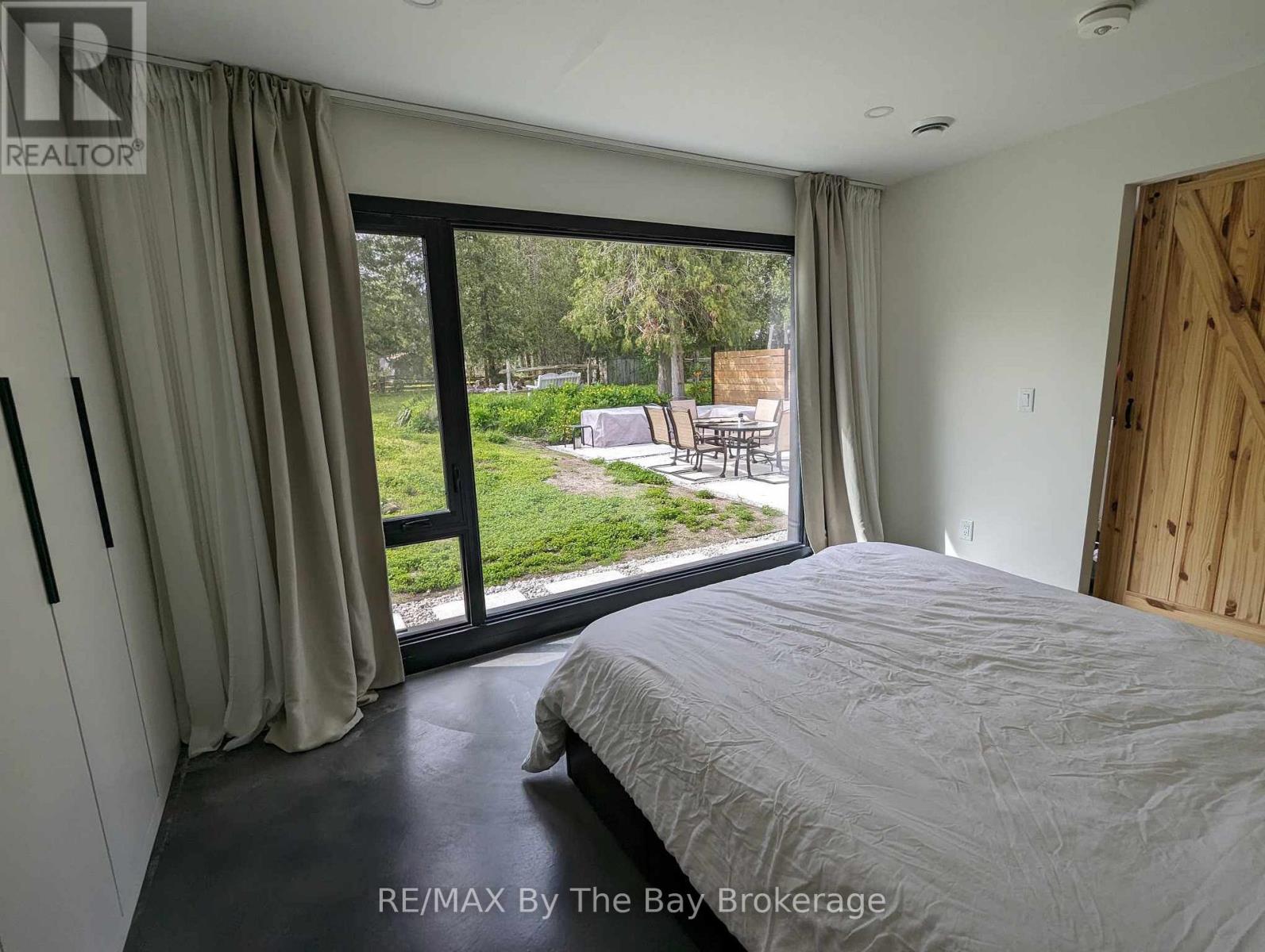 A bedroom with a large bed and a view of a backyard through the sliding glass door.