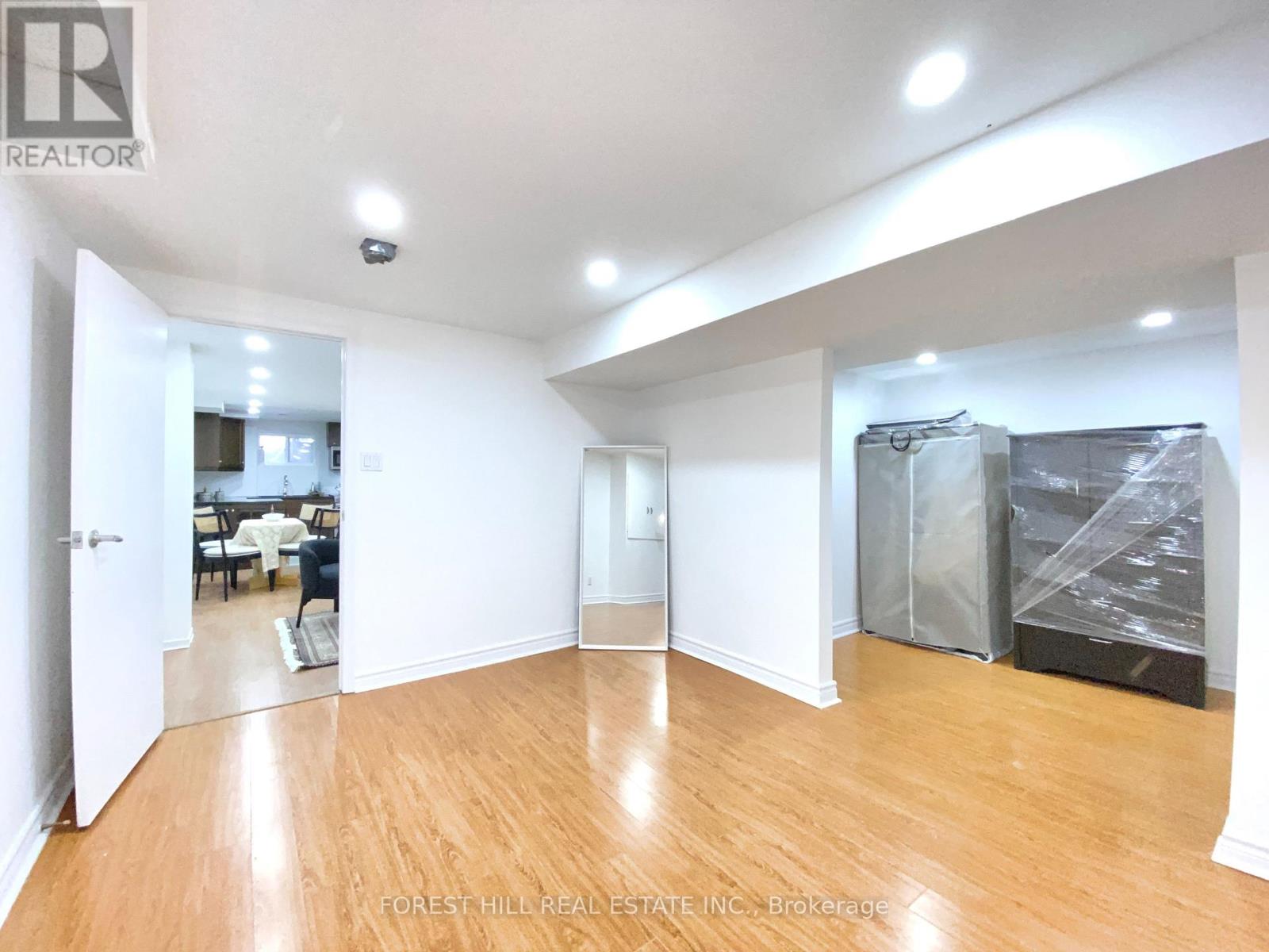 A spacious room with wooden flooring and white walls, currently under renovation with construction materials visible.