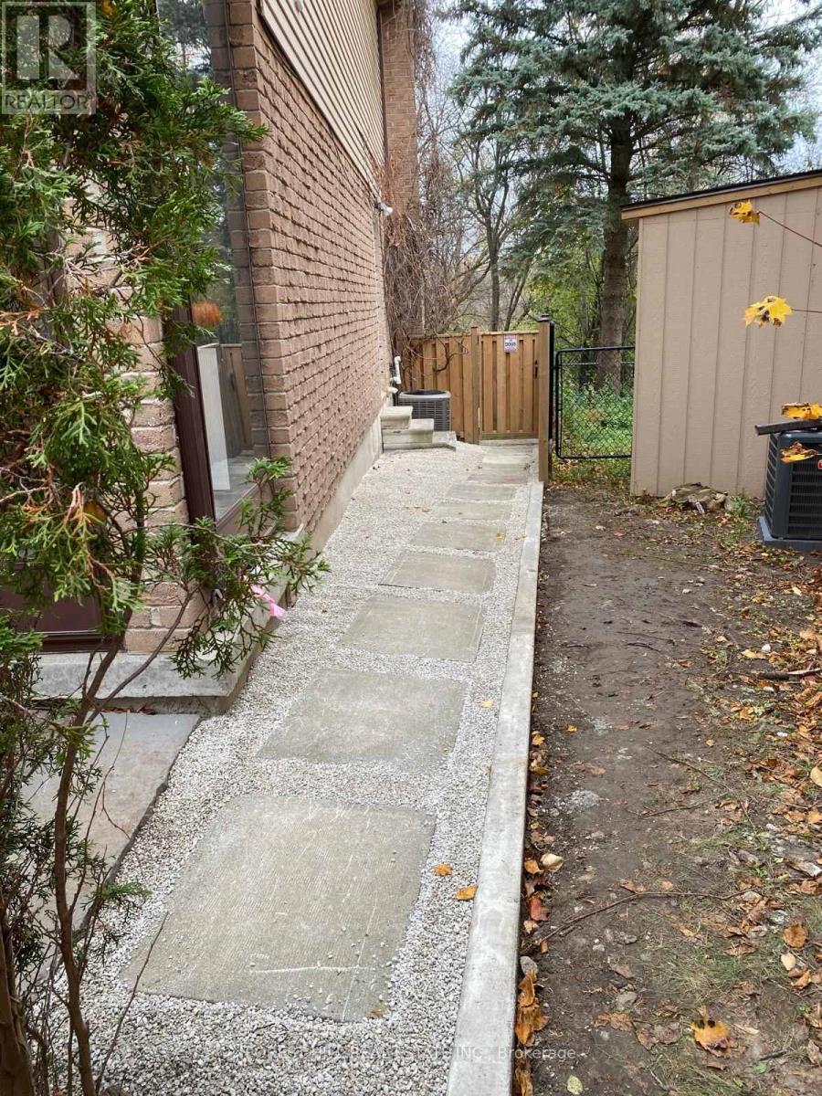 A concrete pathway leads from a building to a wooden structure.