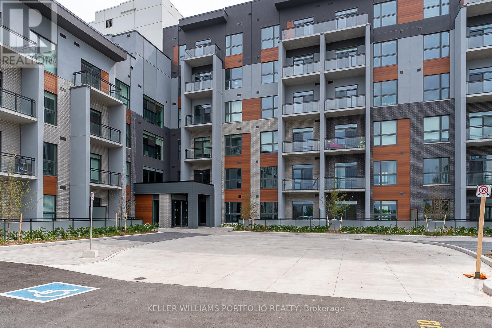 A modern apartment complex with a blue handicap parking sign in front.