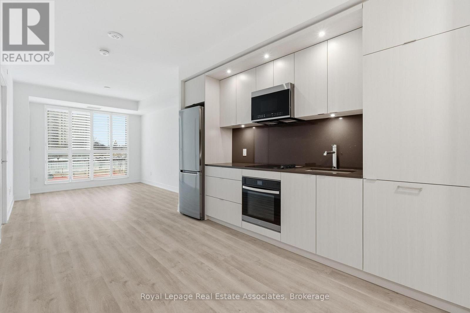 A modern kitchen with white cabinets and a wooden floor.