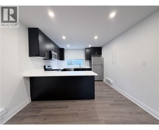 A modern kitchen with black cabinets and a white countertop.