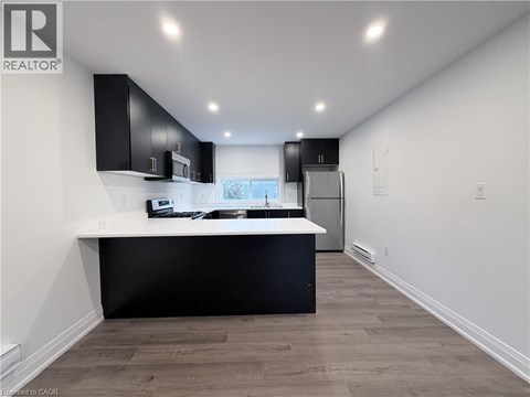 A modern kitchen with black cabinets and a white countertop.