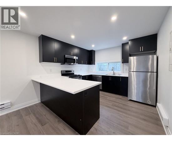 A modern kitchen with black cabinets and a white countertop.