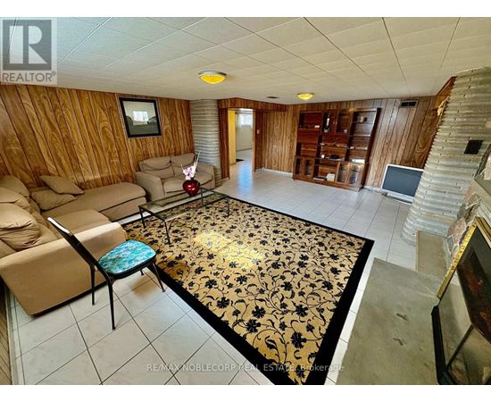 A living room with a wooden wall and a rug with black and gold designs.