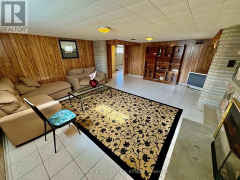 A living room with a wooden wall and a rug with black and gold designs.