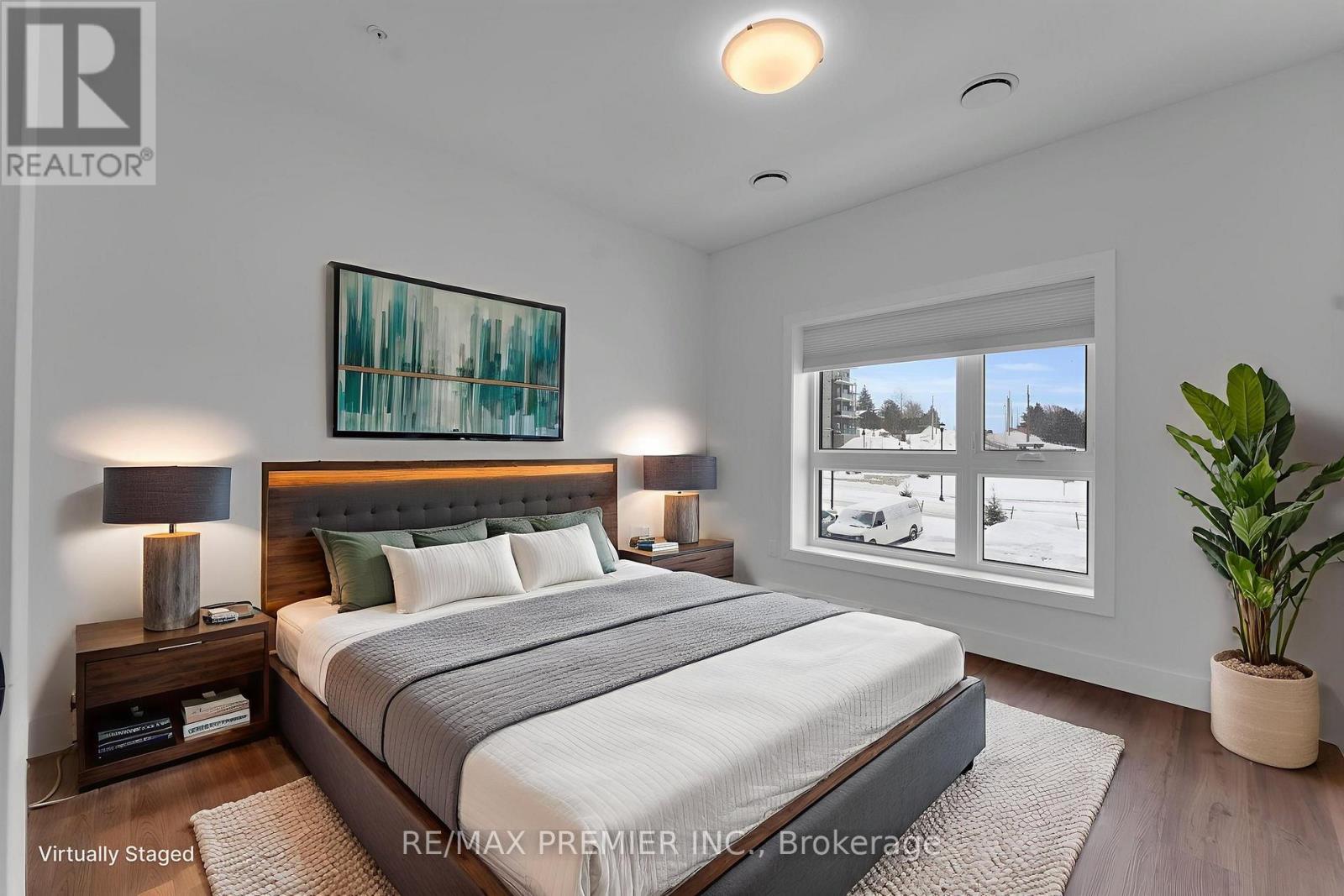 A bedroom with a large bed, a nightstand with a lamp, and a painting on the wall.