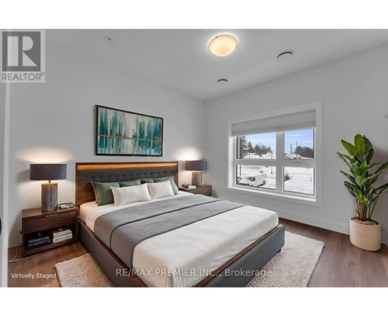 A bedroom with a large bed, a nightstand with a lamp, and a painting on the wall.