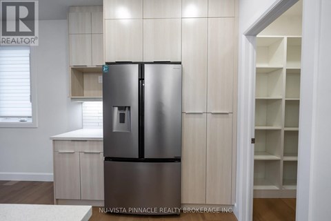 A stainless steel refrigerator in a kitchen with wooden cabinets.