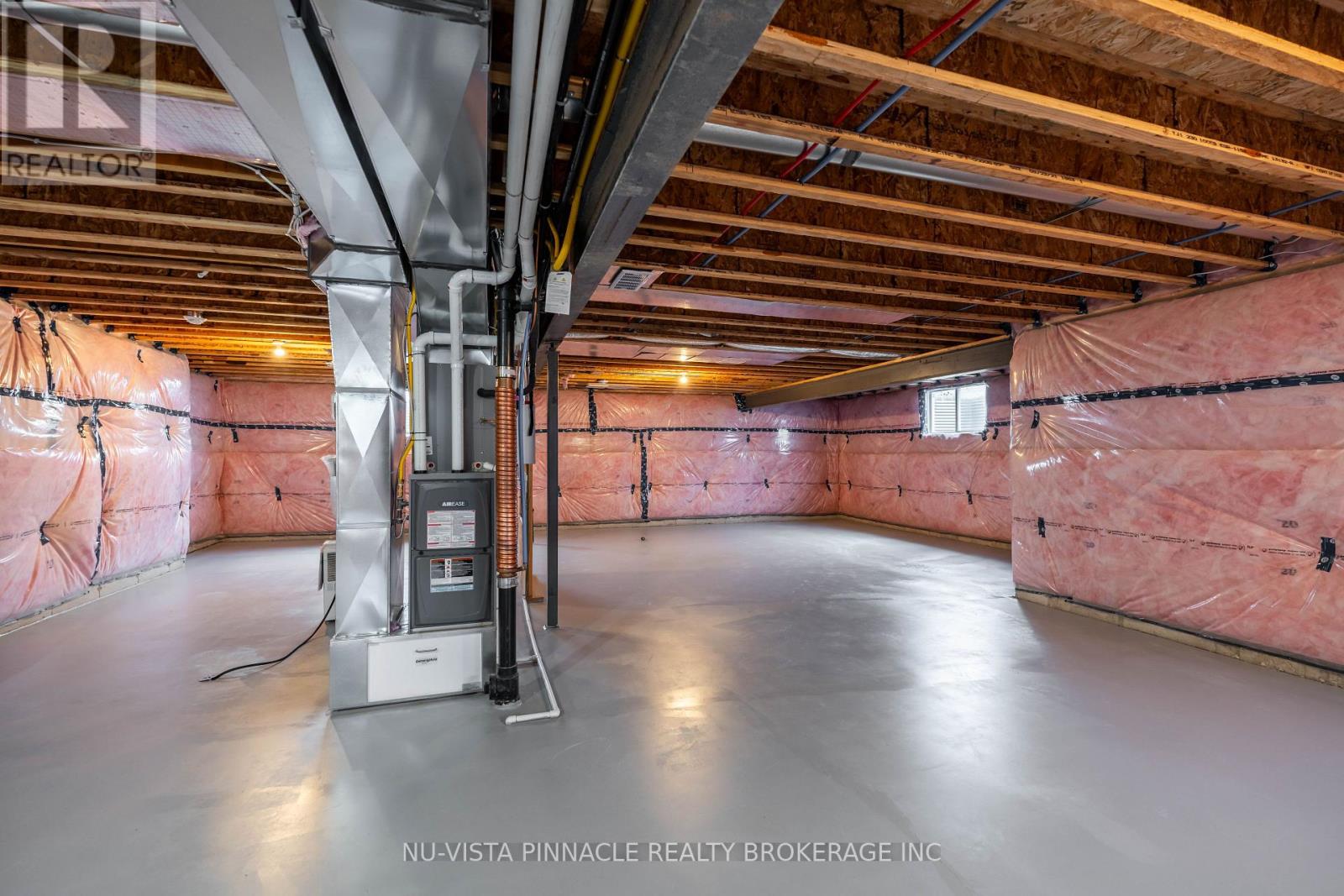 A spacious attic room with insulation and a furnace.