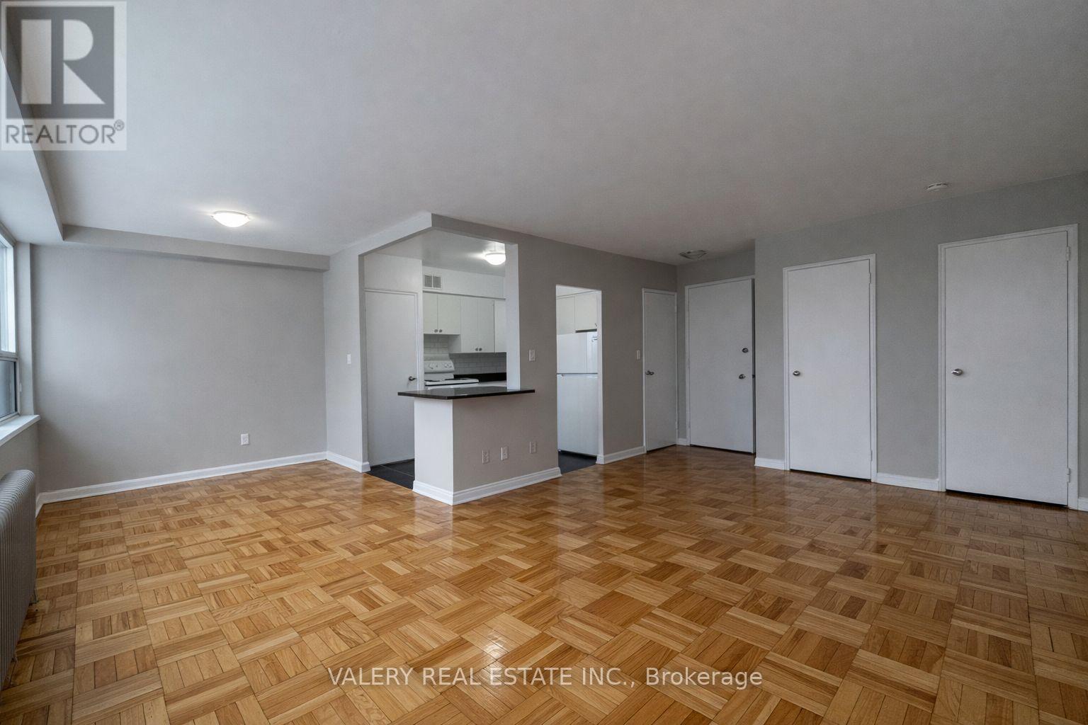 A spacious room with wooden flooring and white walls.
