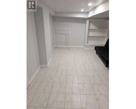 A spacious room with white tiled flooring and a black couch.