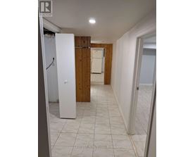 A white refrigerator stands in a kitchen with wooden walls and tile flooring.